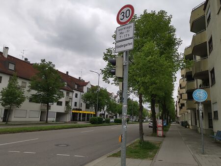 Beispiel-Bild einer Straße mit Bäumen und Verkehrschild, wird im Aritkel mit jeweils anderen Alternativtexten dargestellt